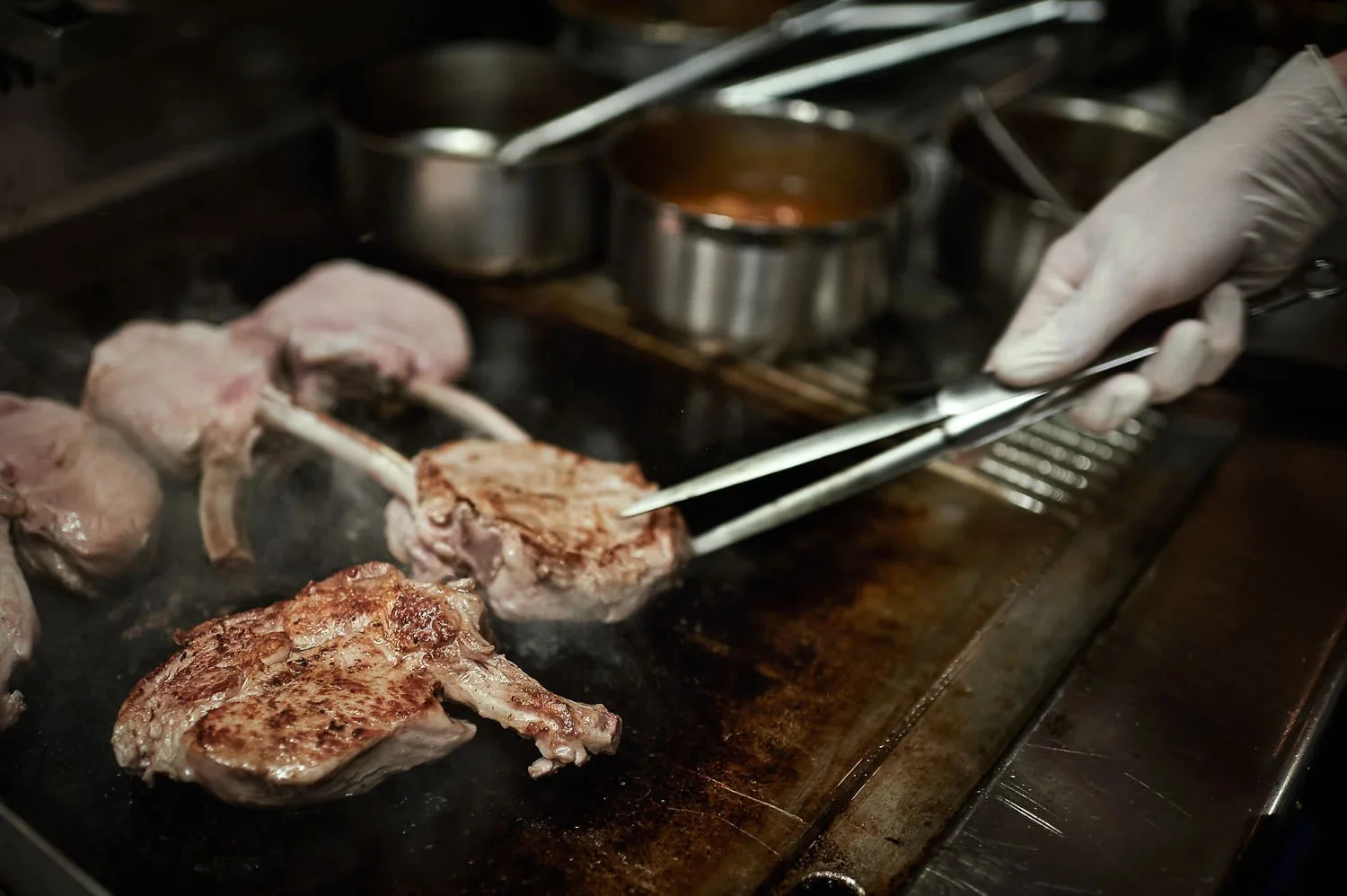 Detailed view of meat cuts searing on a professional kitchen grill.